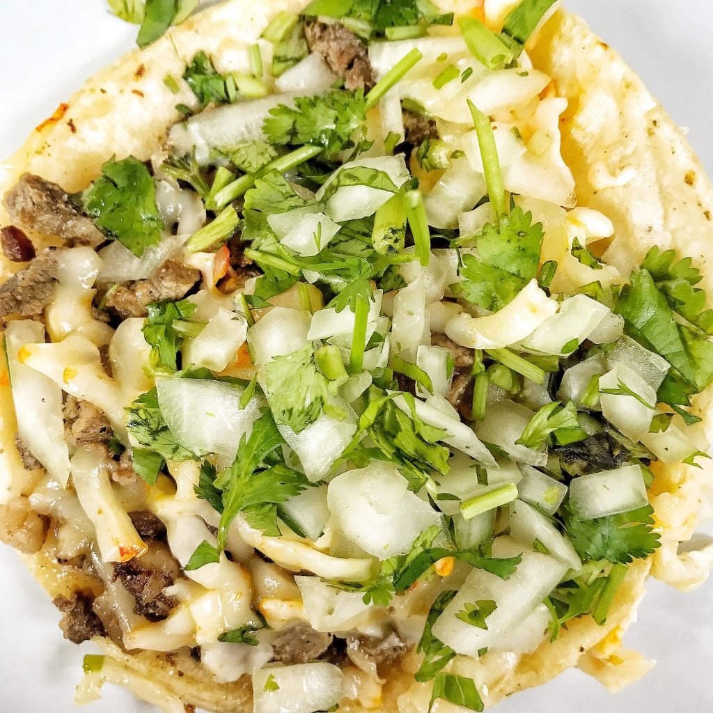 A steak taco with a lot of onion.