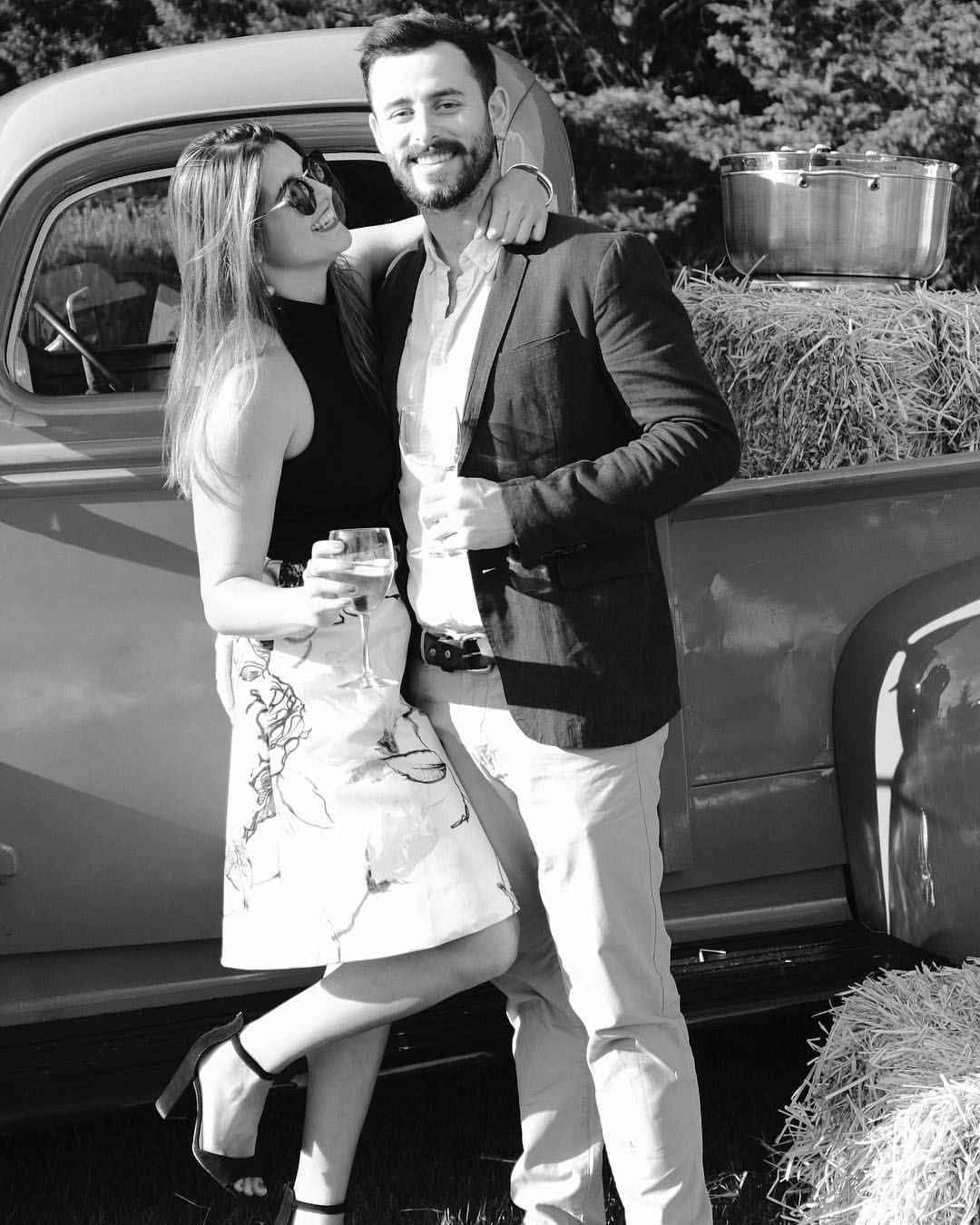 Chris and Andrea in back and white holding drinks in front of a pick up truck.