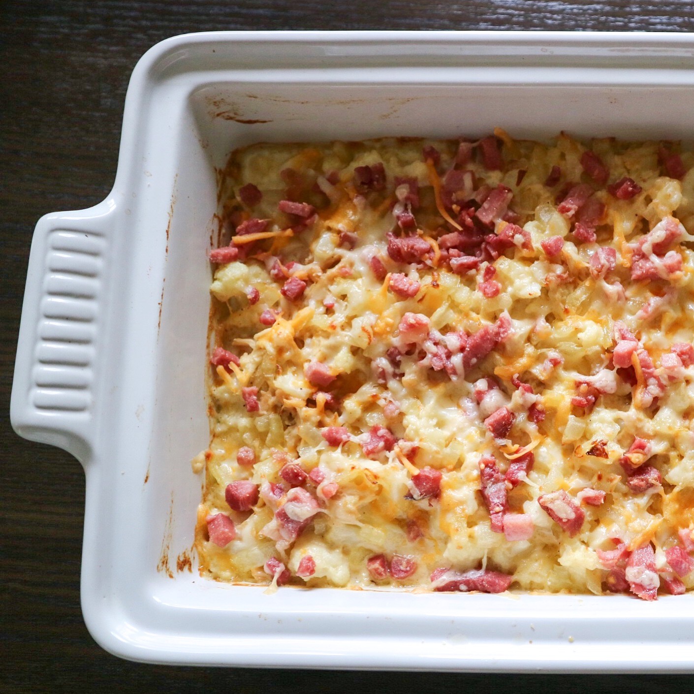 Shredded chicken, cauliflower, and bacon mac and cheese in a white baking dish.