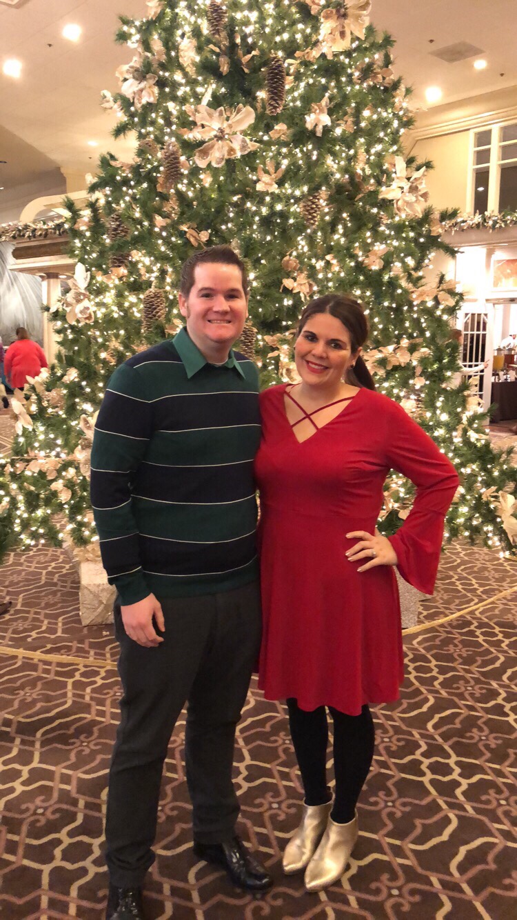 Cocoloses and her husband, Scott, standing in front of a Christmas tree.
