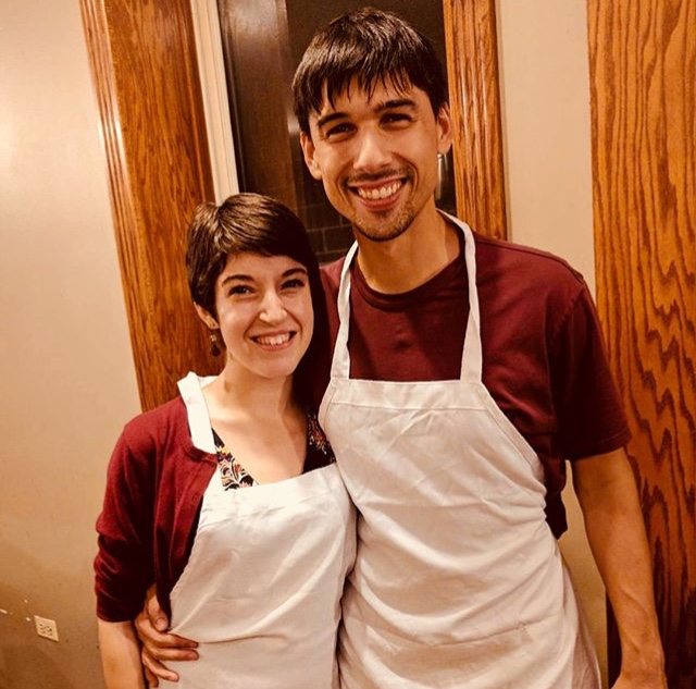 Rachel and her boyfriend wearing white aprons over red shirts.