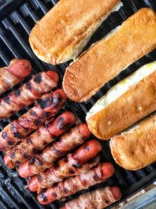 Bacon Wrapped Hot Dogs on the grill next to buns