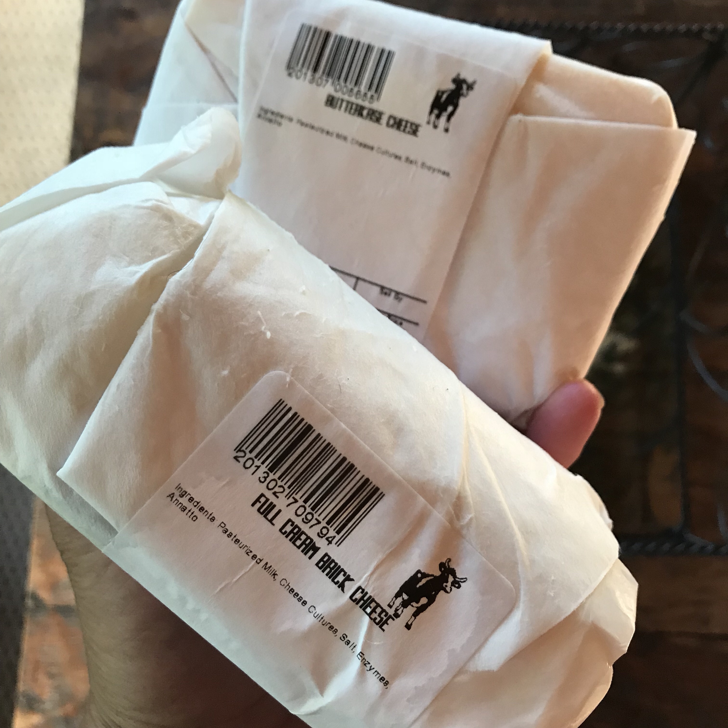 A package of Full Cream brick cheese and a package of Butterkase cheese.