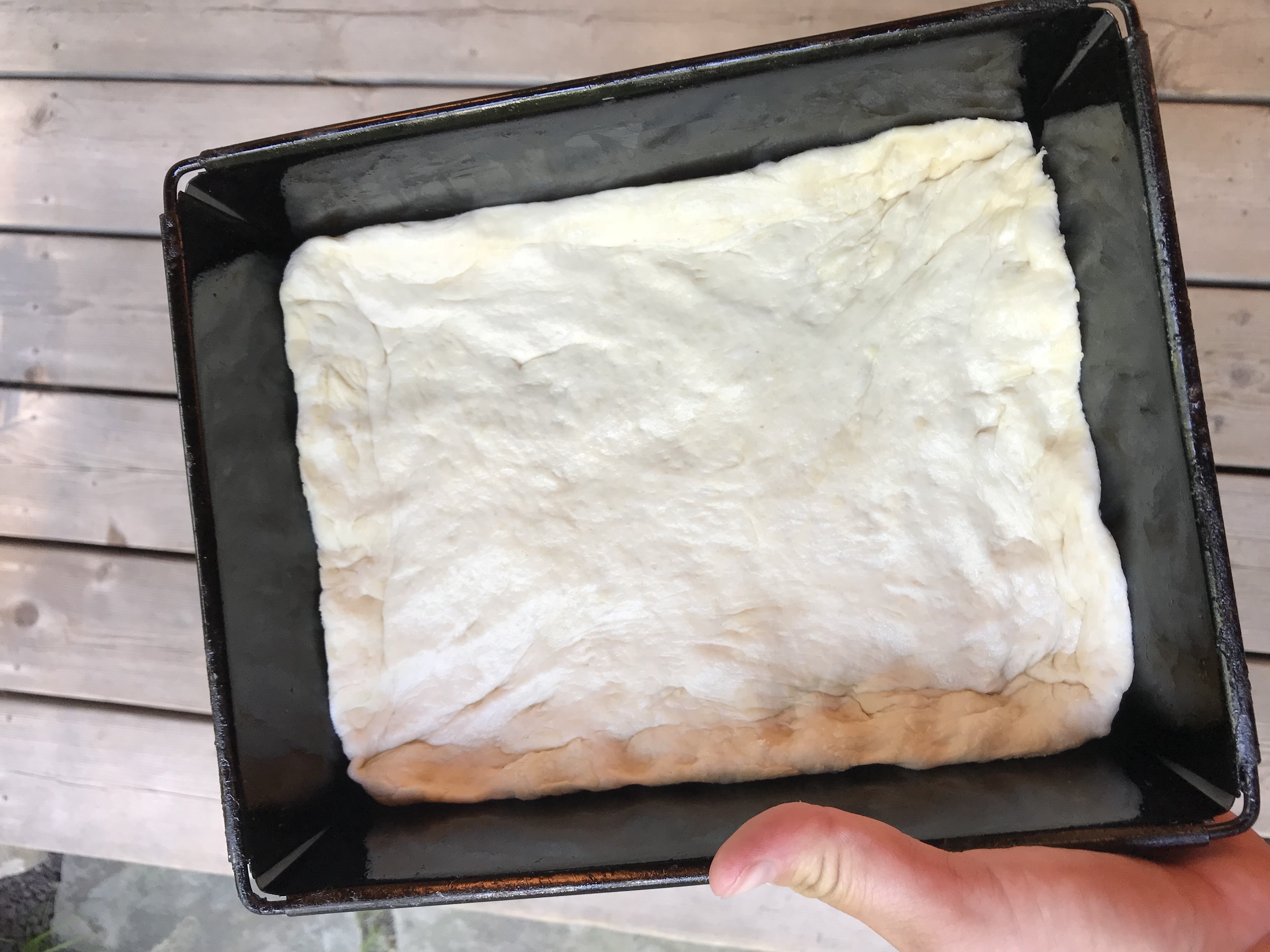 Pizza dough spread out into a rectangle shaped pizza tin.