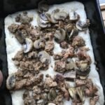 Sausage crumbles and mushroom on raw pizza dough in a square tin.