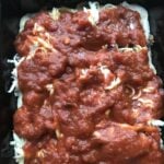 Sausage crumbles, shredded cheese, and mushroom topped with tomato sauce on raw pizza dough in a square tin.