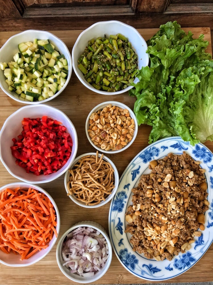 Toppings for Thai lettuce wraps including ground meat, peanuts, and veggies.