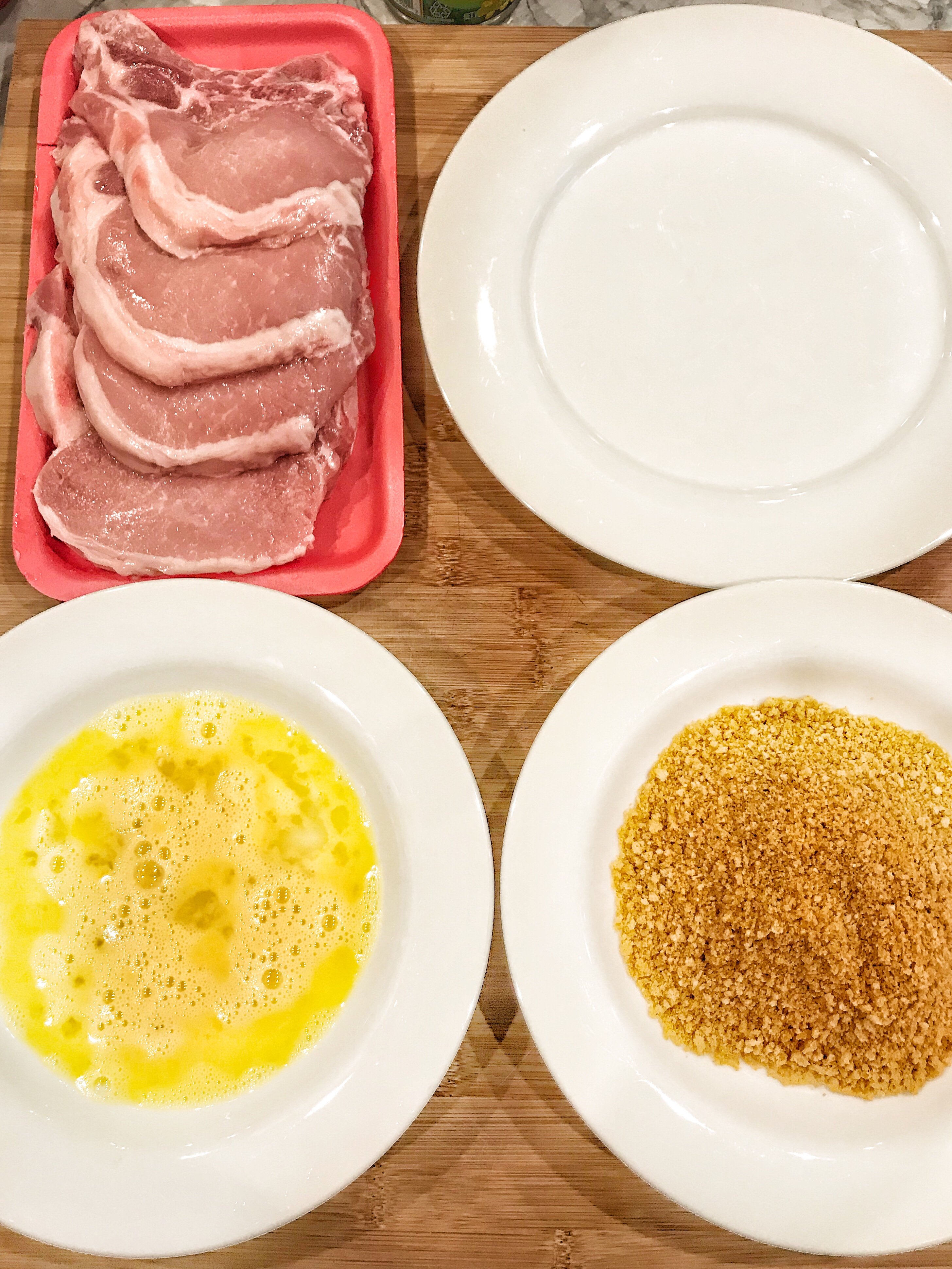A breading station with Bone In Pork Chops, Kraft Foods Oven Fry and egg wash.