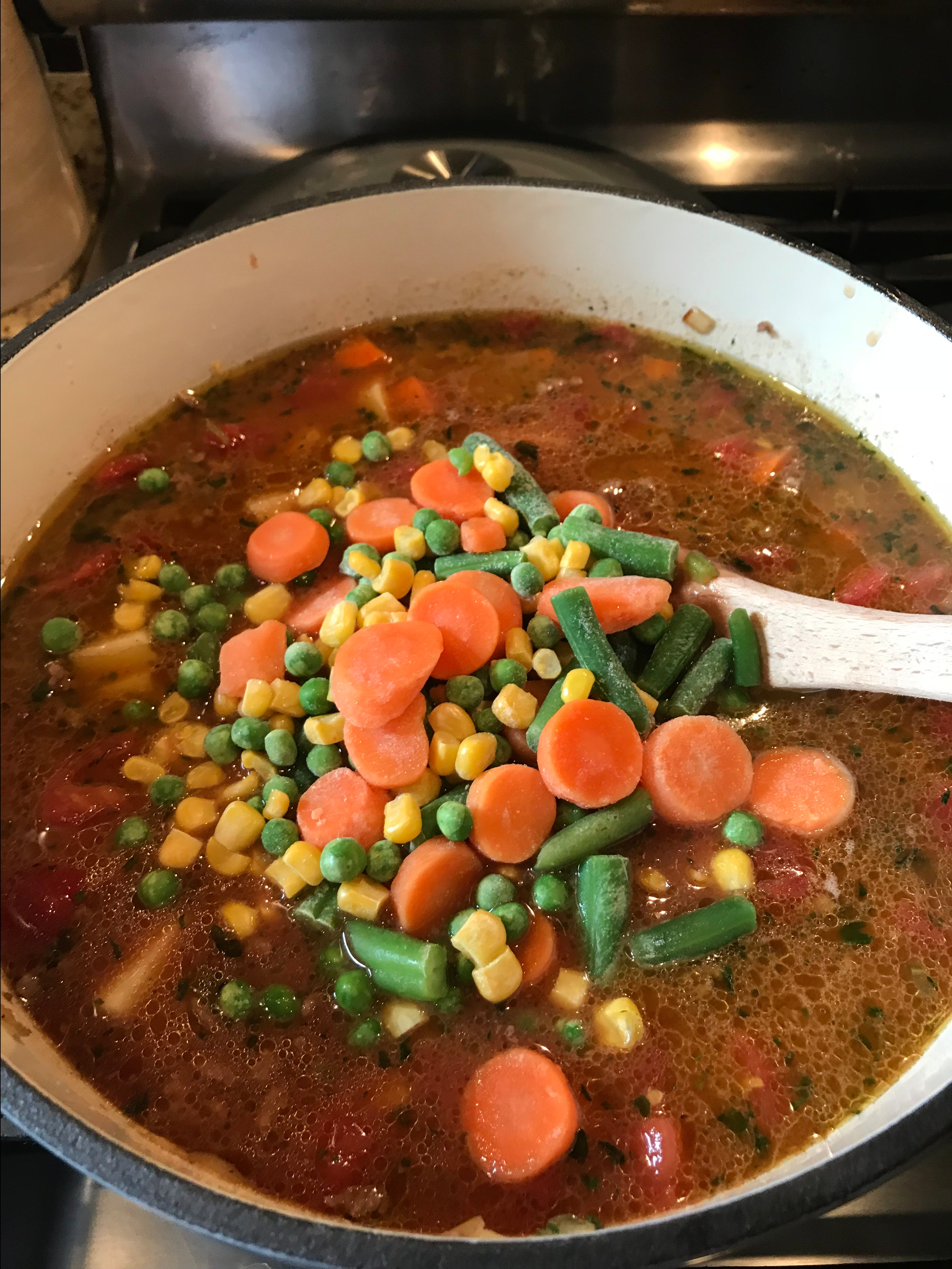 Frozen veggies being mixed into the soup