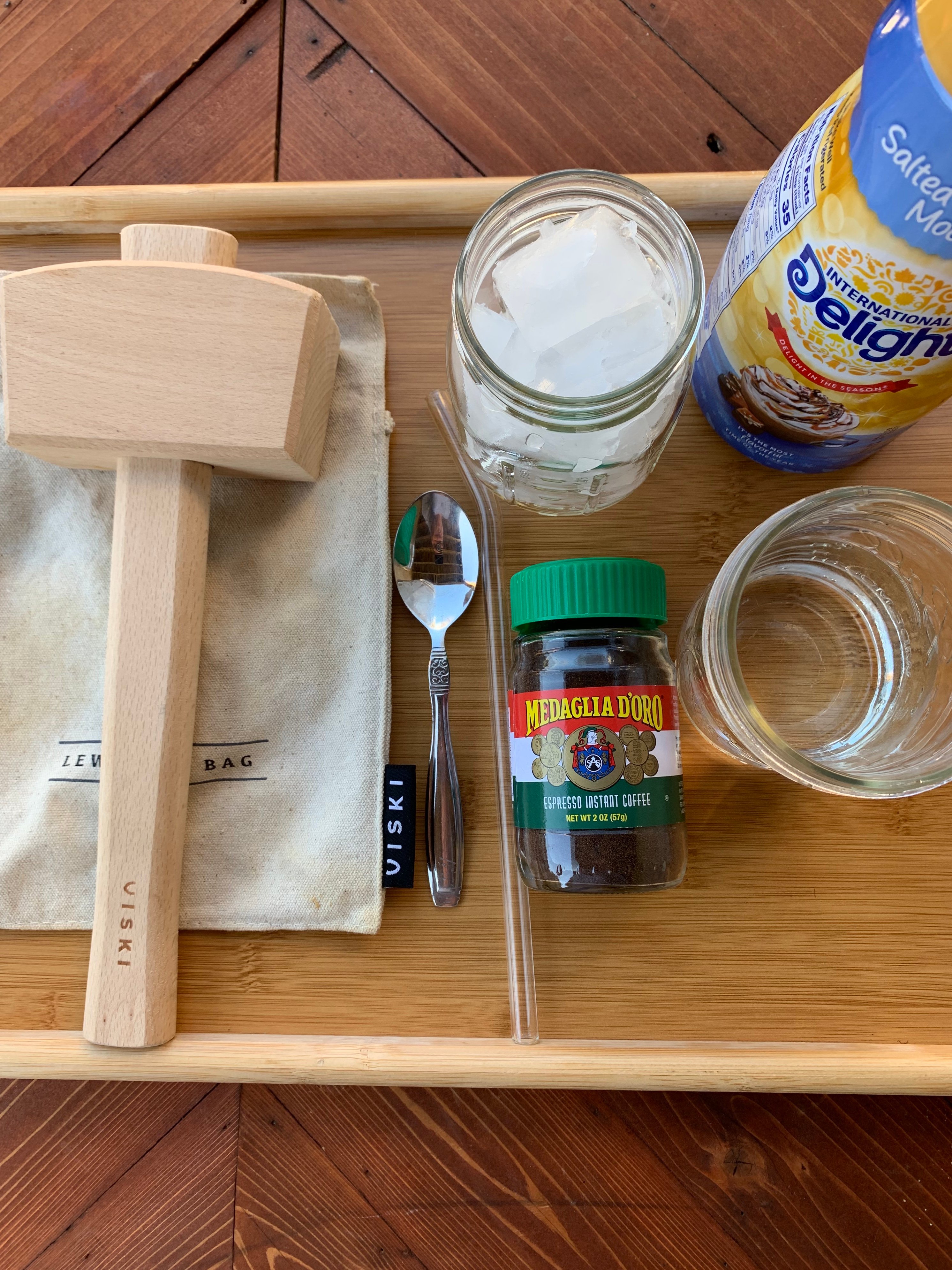 The tools for making the iced coffee including ice, creamer, a mallet, and instant espresso