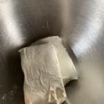 Two blocks of cream cheese in a metal mixing bowl