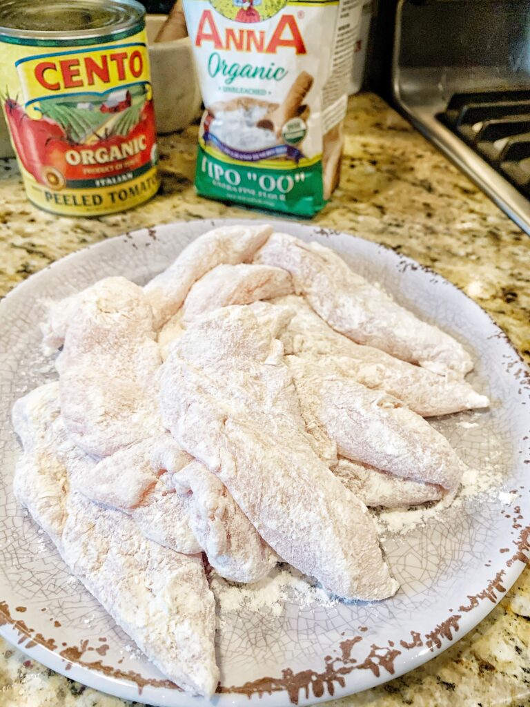 The floured chicken pieces on a plate