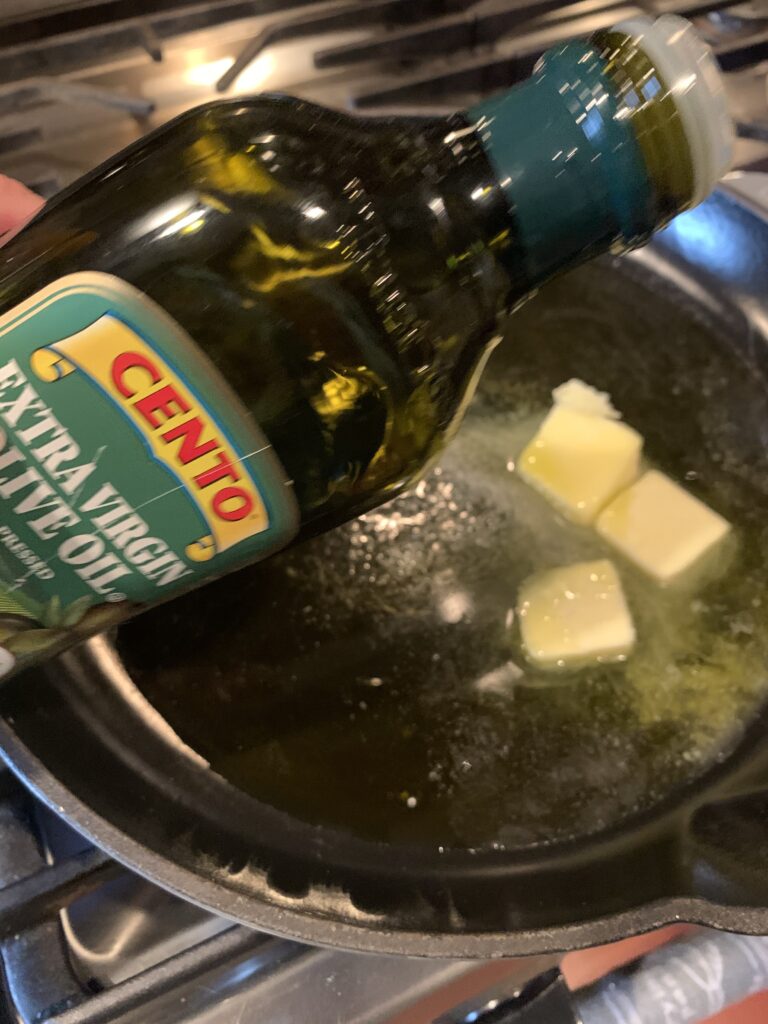 Olive oil being poured on top of melting butter in a pan