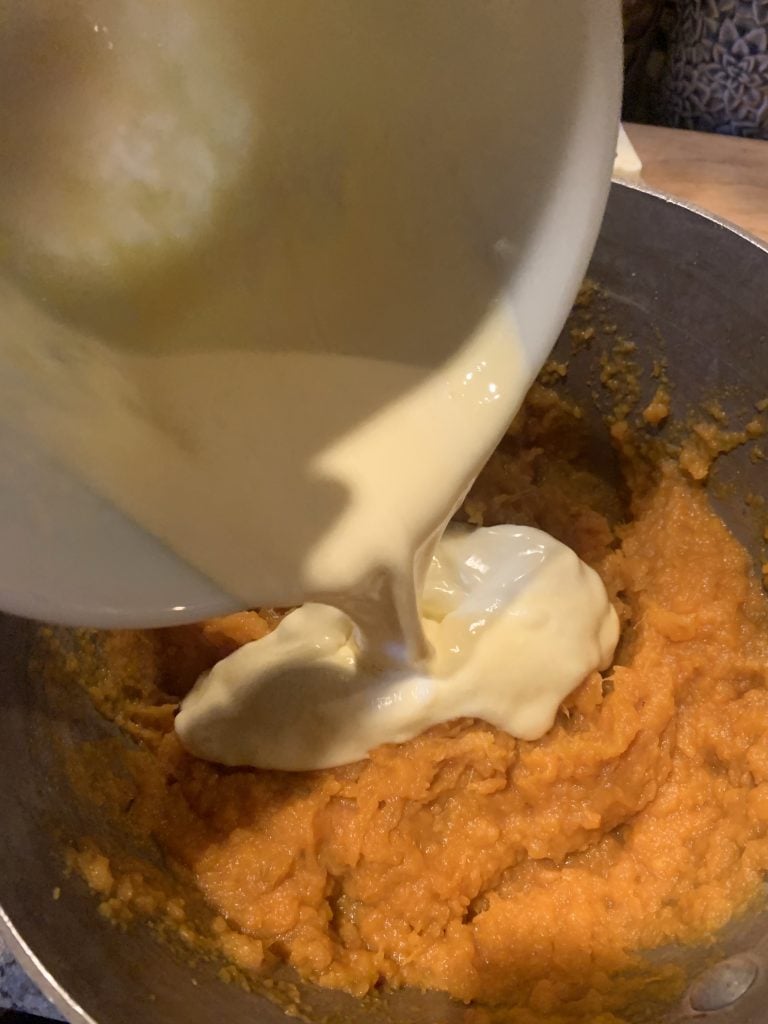 Mashed sweet potatoes with heavy cream whisked with eggs being folded into it