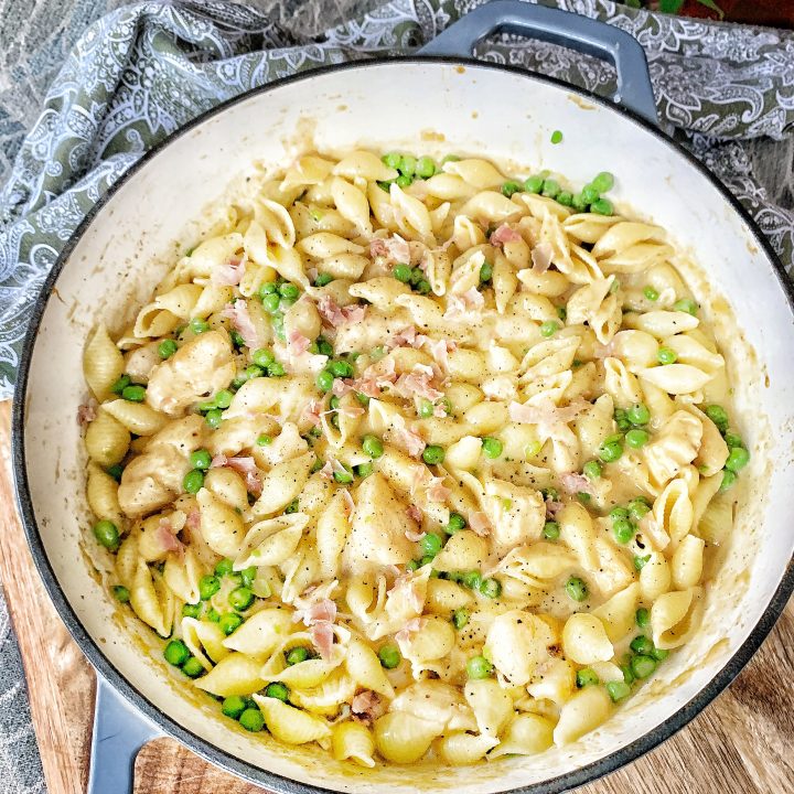 Skillet with pasta shells, chicken, peas, prosciutto and cheese sauce