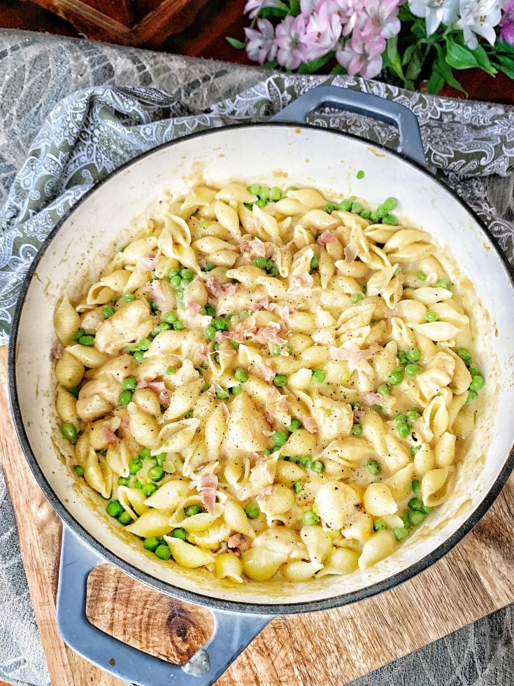 Skillet with pasta shells, chicken, peas, prosciutto and cheese sauce