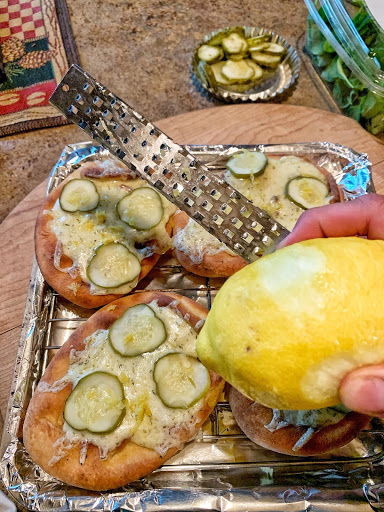 A lemon being zested over the pickle flat breads