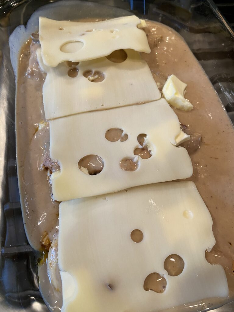 Swiss cheese placed over the sauce-covered chicken before baking