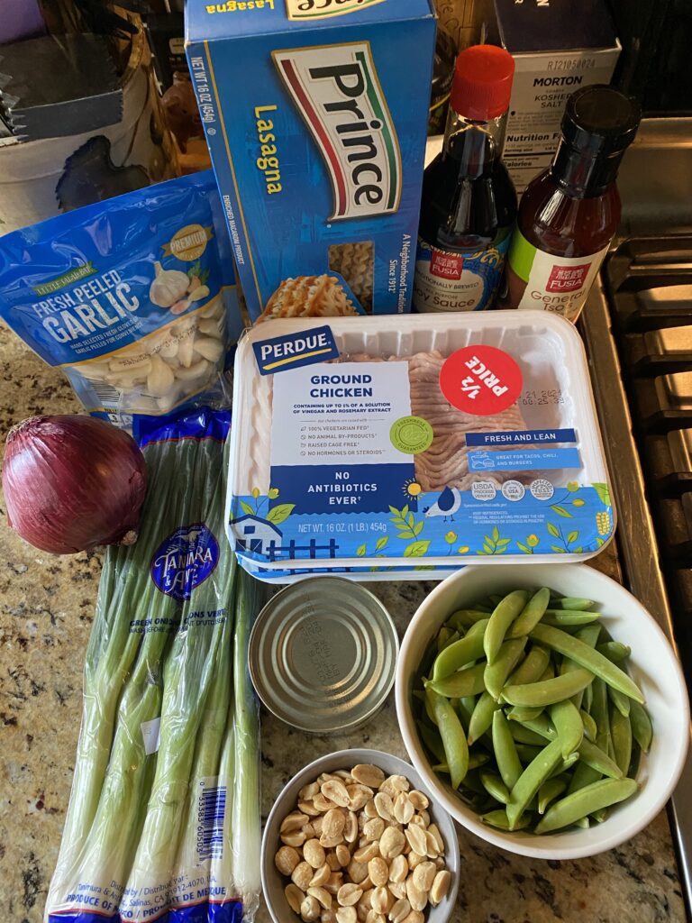 The ingredients for the dumpling bowl, including ground chicken, peapods, peanuts, onion, garlic, lasagna noodles, soy sauce, and General Tso sauce
