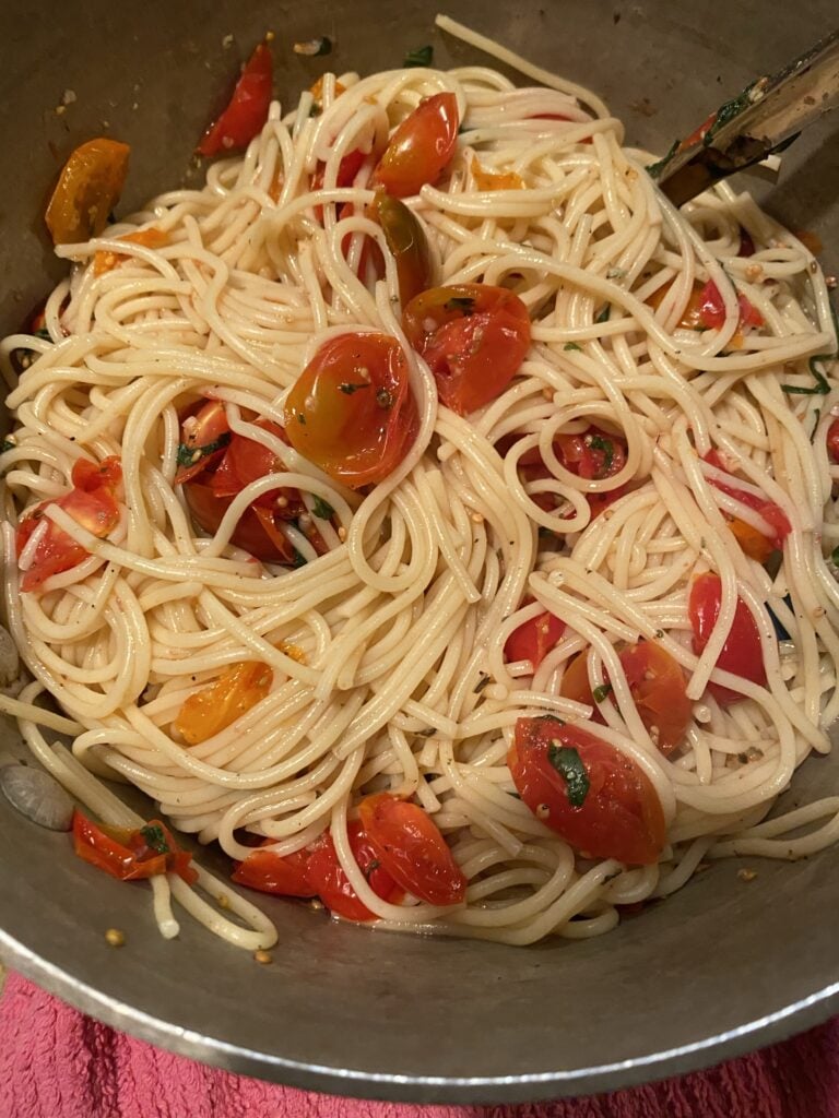 Pasta and grape tomato mixture being mixed in a pot