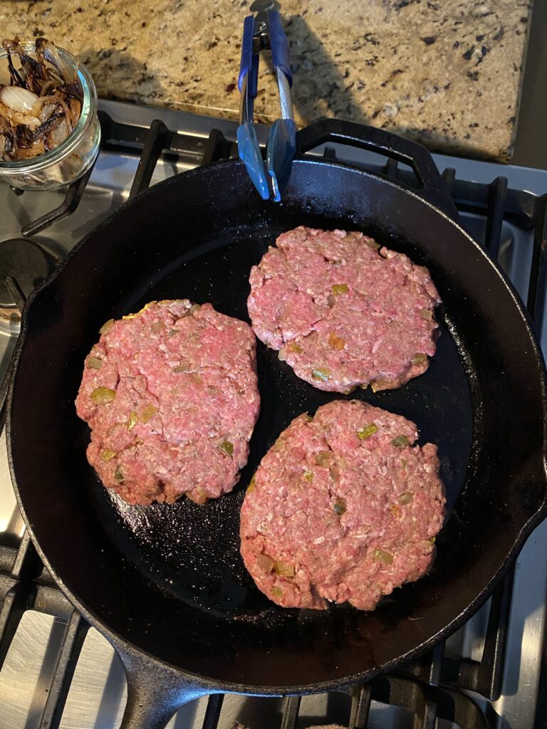 Burger patties cooking in a cast iron
