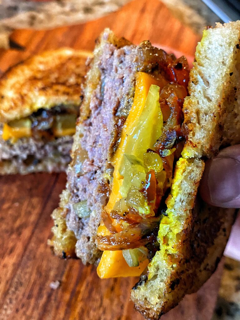 A close up of a delicious patty melt with pickles