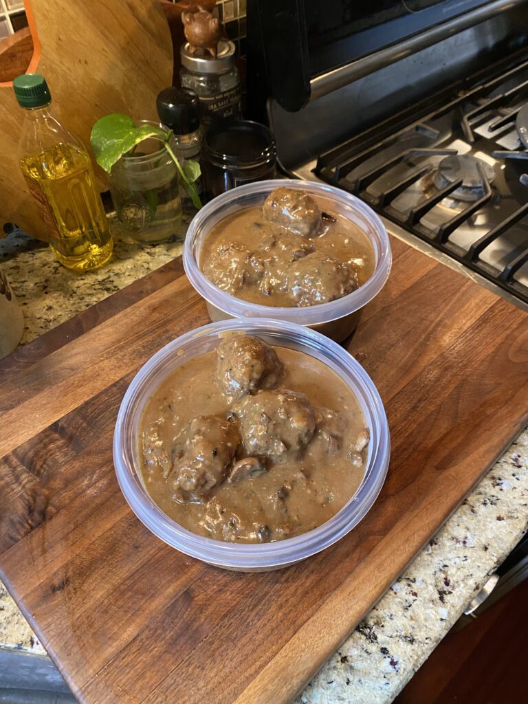 Meatballs with gravy portioned into two plastic containers