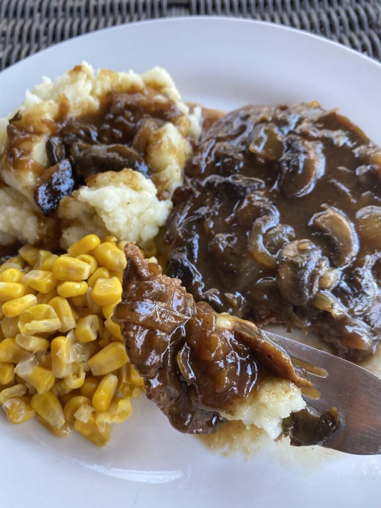 A forkful of steak, mushrooms, potatoes, and corn