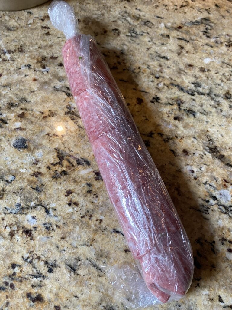The salami rolled up in plastic wrap