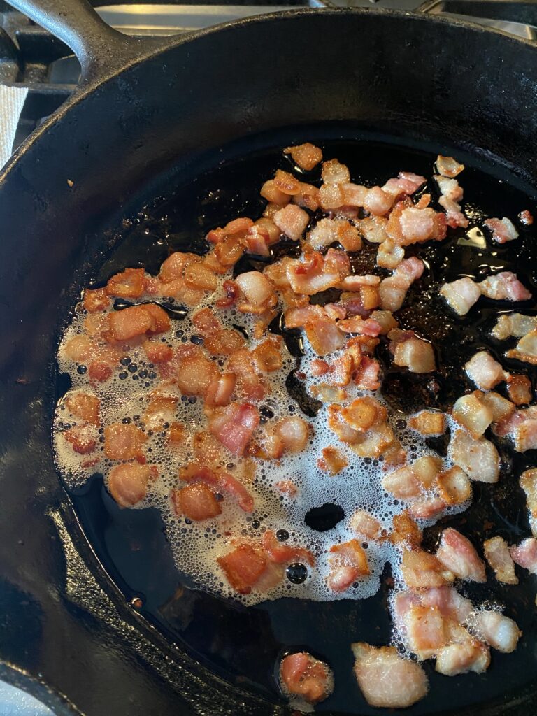 Diced bacon cooking up in a pan