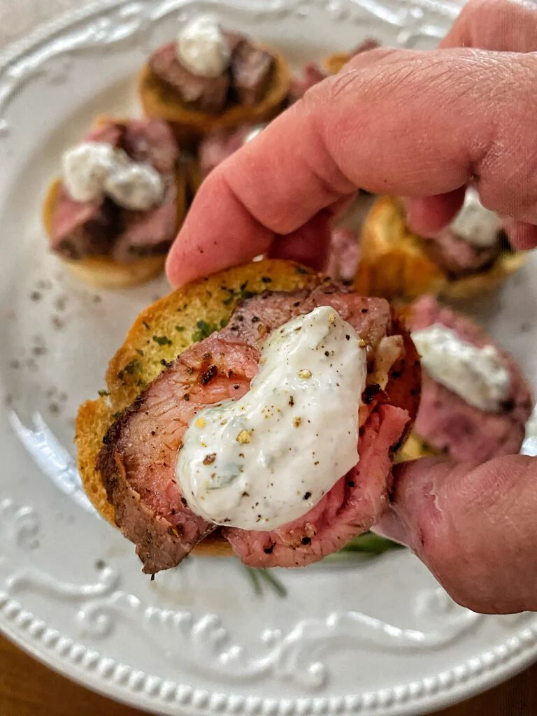 Sliced sirloin steak served on toasted garlic bread with horseradish cream for an elegant party appetizer.