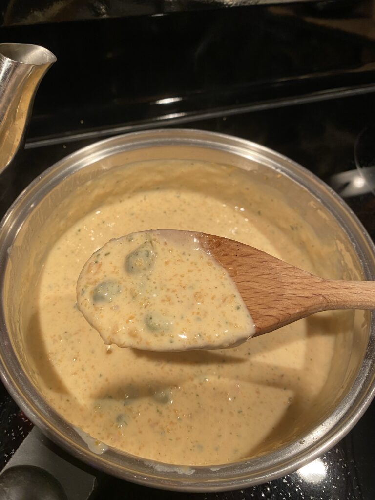 A ladle of the creamy meatball sauce above a pot of the same