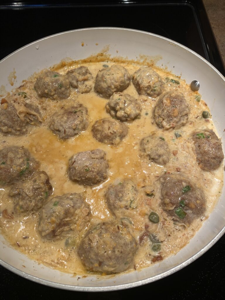 Meatballs cooking in the sauce in a pan