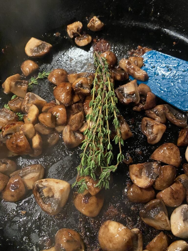 Mushrooms and thyme cooking in a skillet