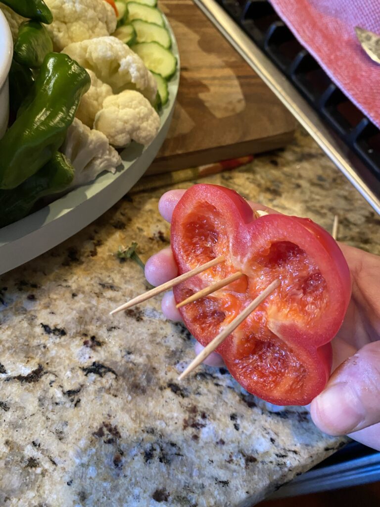 A piece of a bell pepper with three tooth picks sticking out of it