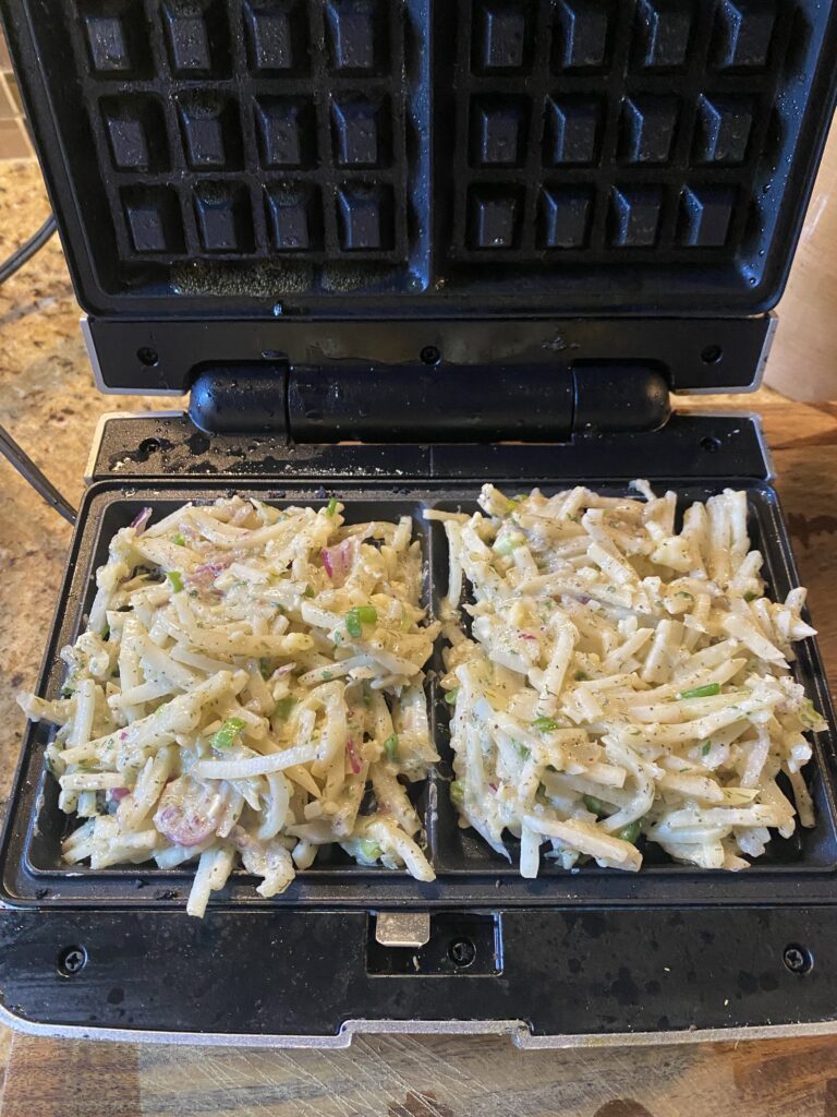 The hash brown mixture in a double waffle iron