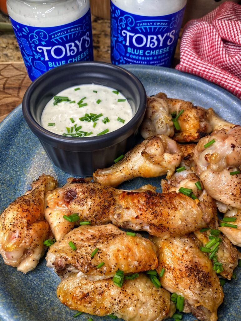 The finished chicken wings on a plate with a cup of blue cheese dipping sauce