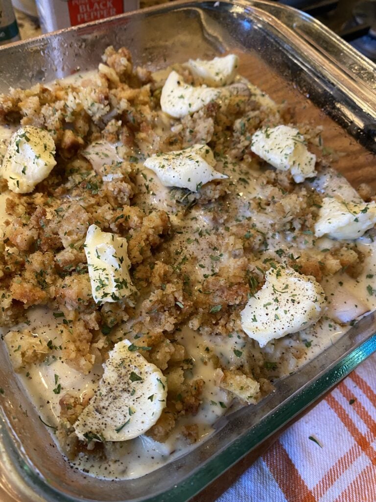 The turkey roll ups in a baking dish covered with stuffing and butter