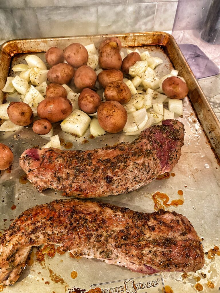 Pork tenderloins, potato, and onions on a baking dish