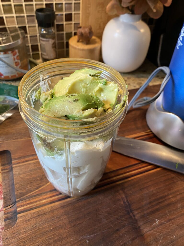 Avocado and sour cream in a blender container