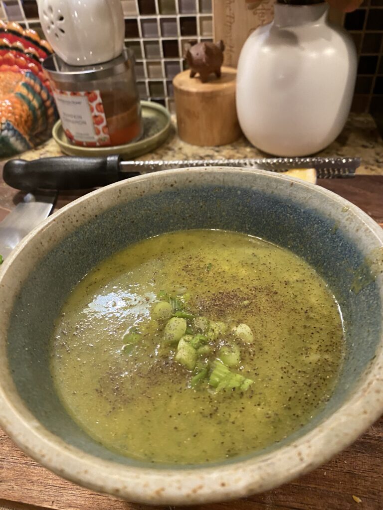 A bowl of broccoli asparagus soup topped with green onions