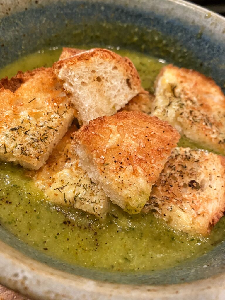 A close up of croutons in broccoli asparagus soup