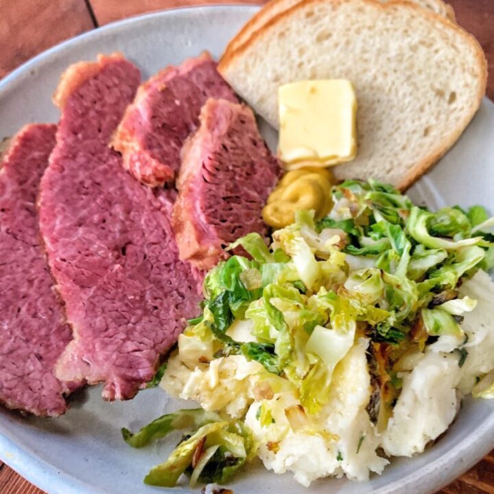 Slices of corned beef on a plate with potatoes and bread