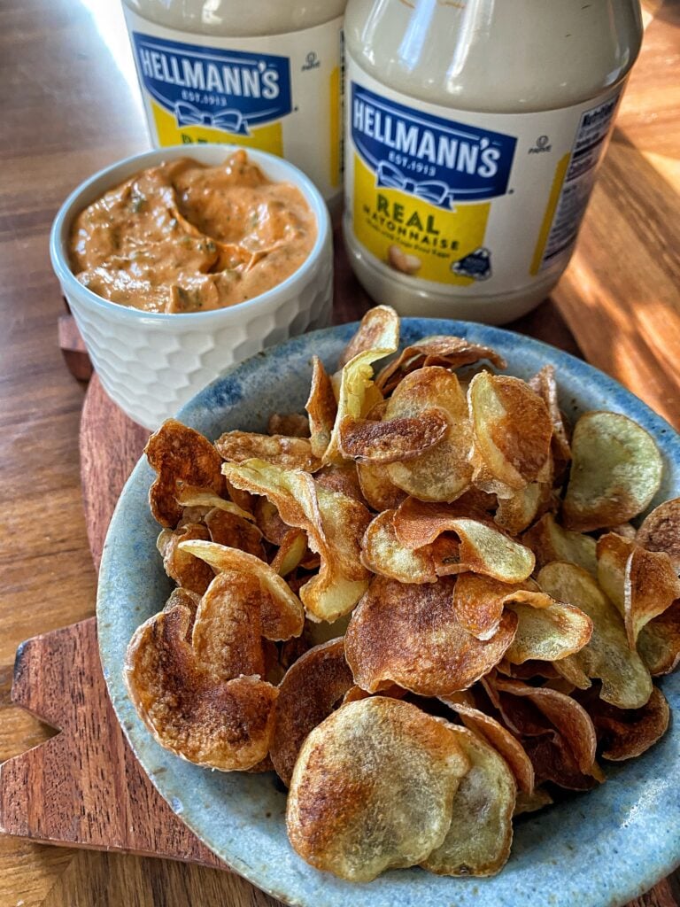 A bowl of potato chips next to the tomato dip