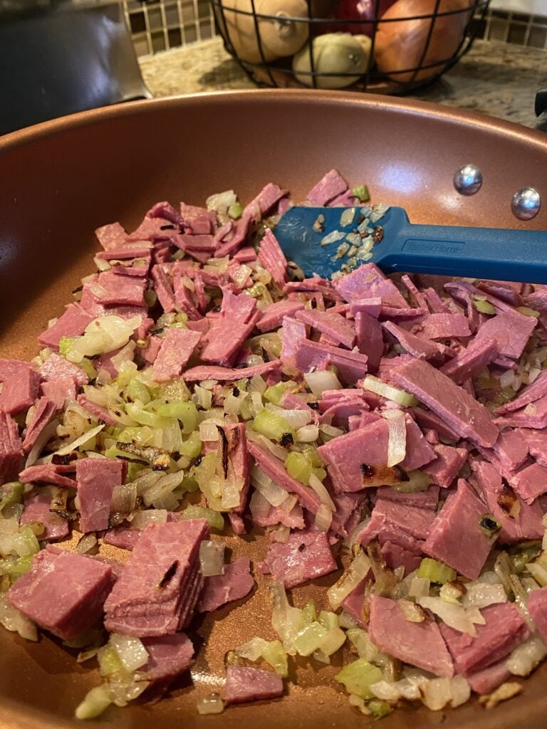 Slices of corned beef cooking in a pan