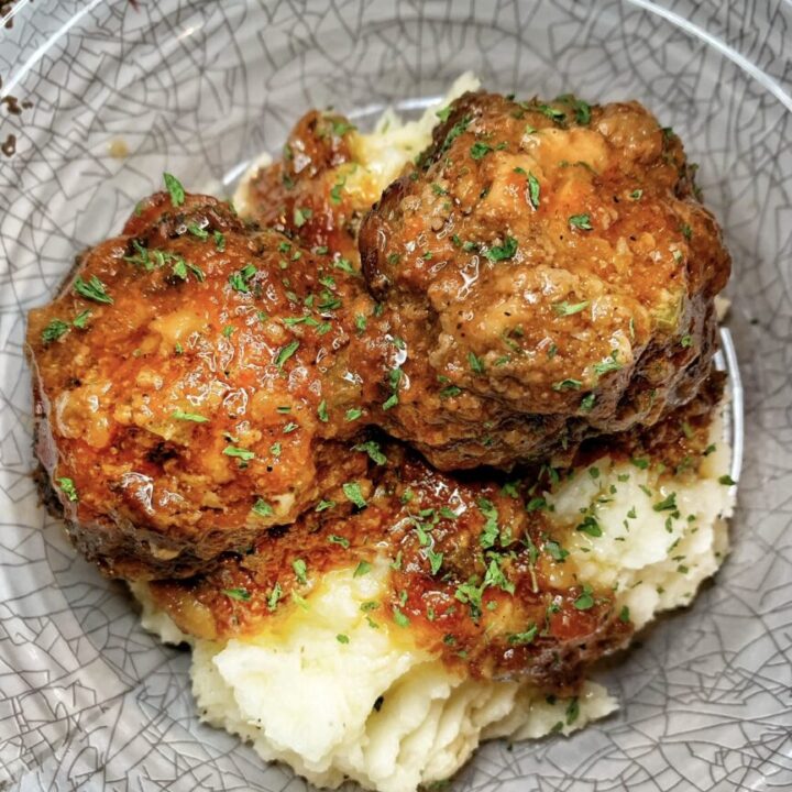 Two meatloaf meatballs over mashed potatoes