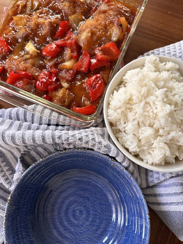 The finished sweet and sour chicken bake next to a small bowl of white rice