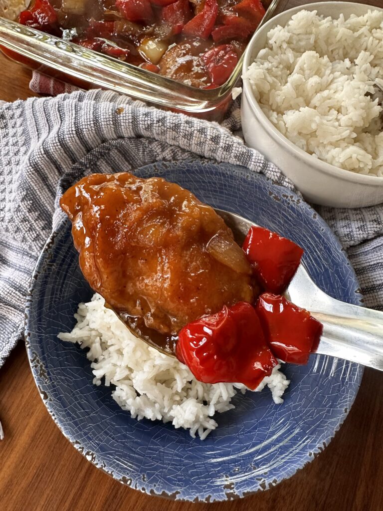 A spoon of sweet and sour chicken with peppers
