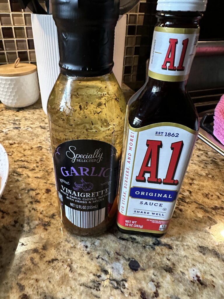 A bottle of garlic vinaigrette next to a bottle of A1 steak sauce