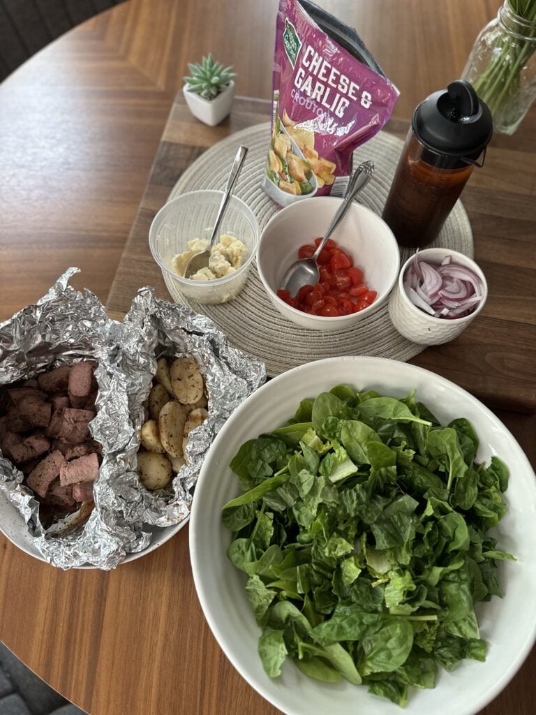 The components for the steakhouse salad including potatoes, steak, croutons, cheese, tomatoes, and onions